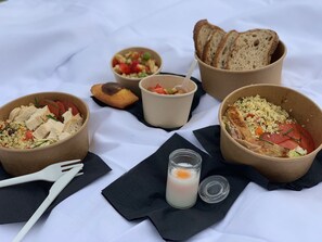 A meal setup with bowls of food, a candle, and a glass of milk on a white tablecloth. - Hotel SPA Piscine le Petit Castel (Beuzeville)