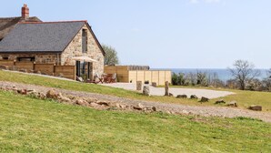 A stone house with a sloped roof and a wooden deck. - Apple Blossom Barn (Penzance)