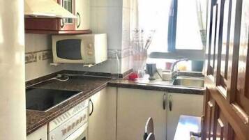 Een koelkast, kookgerei, borden en bestek, een eettafel