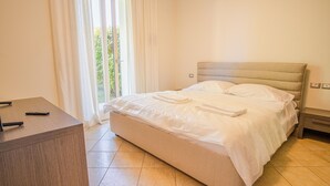 A hotel room with a bed, a desk, and a window with curtains. - Endless Summer Sirmione - Italian Homing (Sirmione)