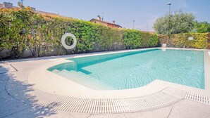 A rectangular swimming pool with a clear blue water surface, surrounded by a tiled deck and a low hedge. - Endless Summer Sirmione - Italian Homing (Sirmione)