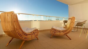 Dos sillones de mimbre con cojines en un balcón con una vista despejada del cielo.