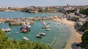 Une ville côtière dotée d’un port de plaisance rempli de bateaux, d’une plage de sable et de bâtiments qui se dressent à l’arrière-plan.