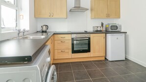 A modern kitchen with wooden cabinets, a stainless steel sink, a microwave, a toaster, and a dishwasher.