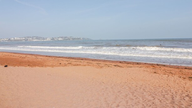 A beach with a clear sky and waves.