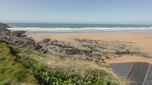A coastal landscape with a sandy beach, rocky outcrops, and a clear sky. - Fistral Watch (Newquay)