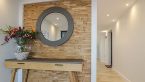 A modern reception area with a wooden wall, a round mirror, and a vase with flowers. - Fistral Watch (Newquay)
