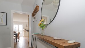 A modern kitchen with a wooden countertop, a vase with flowers, and a large mirror. - The Hideaway Beach House (New Romney)