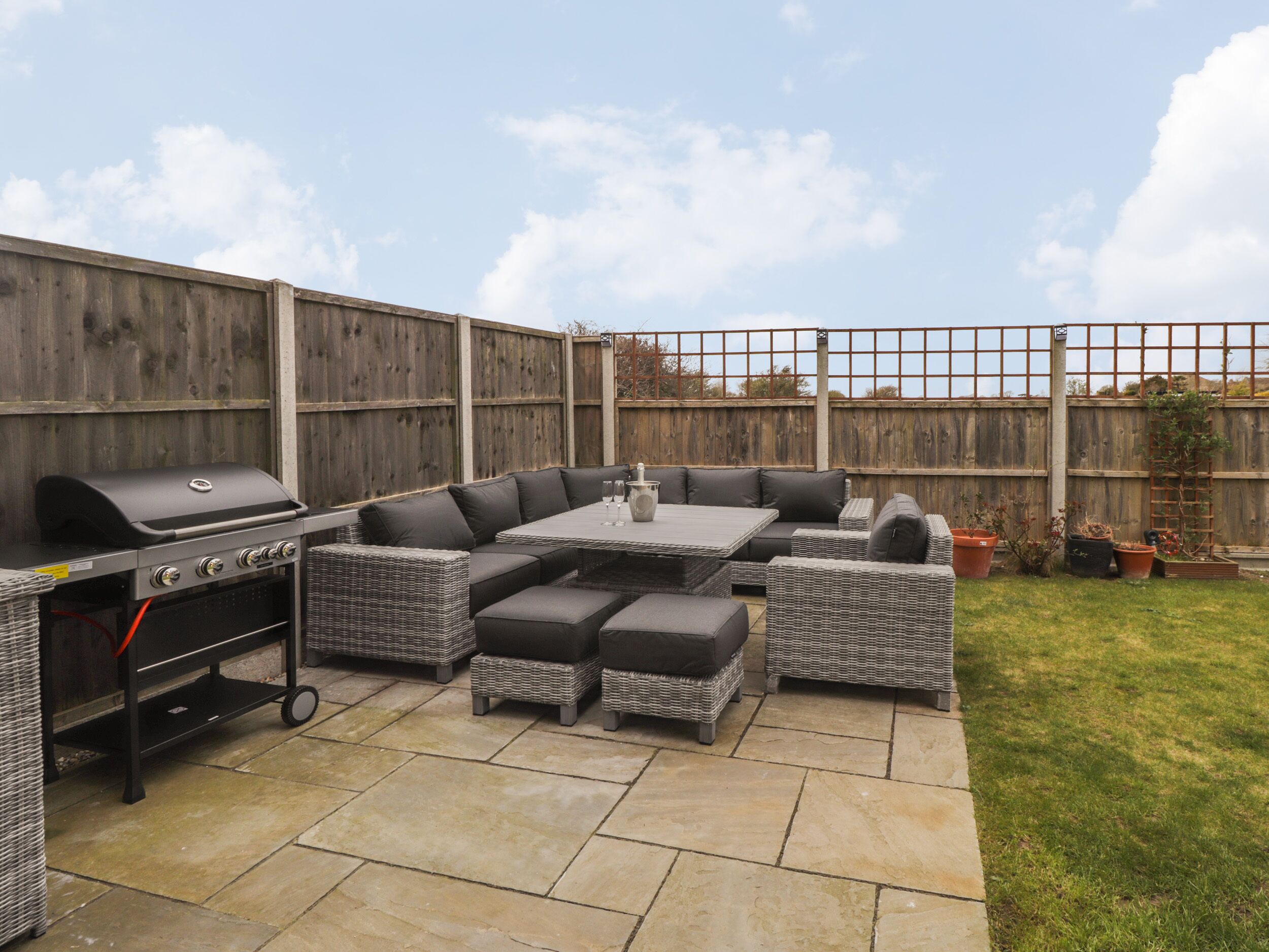 A backyard with a barbecue area, a large sectional sofa, and a dining table.