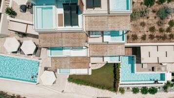 A modern multi-level residential building with a large swimming pool, outdoor seating, and a landscaped garden.
