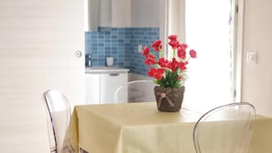 A dining table with a yellow tablecloth, a clear chair, and a small potted plant with red flowers. - Holiday Home in Favignana near Beach (Favignana)