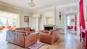 Amplia sala de estar con un amplio sofá de cuero marrón, chimenea y piso de madera en patrón de espiga.