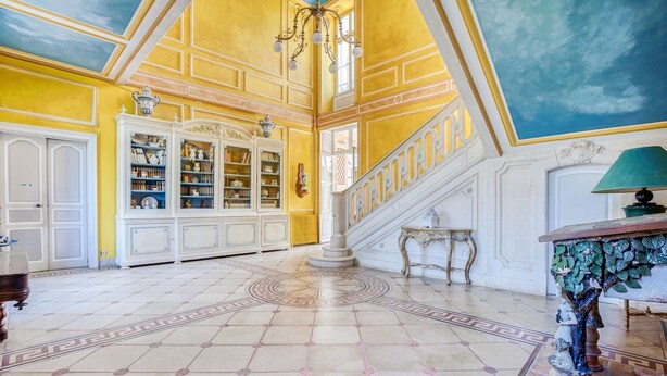 Un vestíbulo imponente con techo alto, una escalera y una amplia biblioteca.