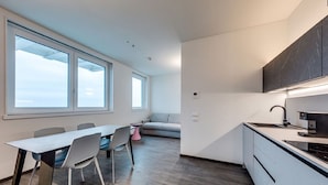 A modern kitchen with a built-in stove, a dining area with a table and chairs, and large windows providing natural light. - Belvilla by OYO Appartamento N7 (Venice)