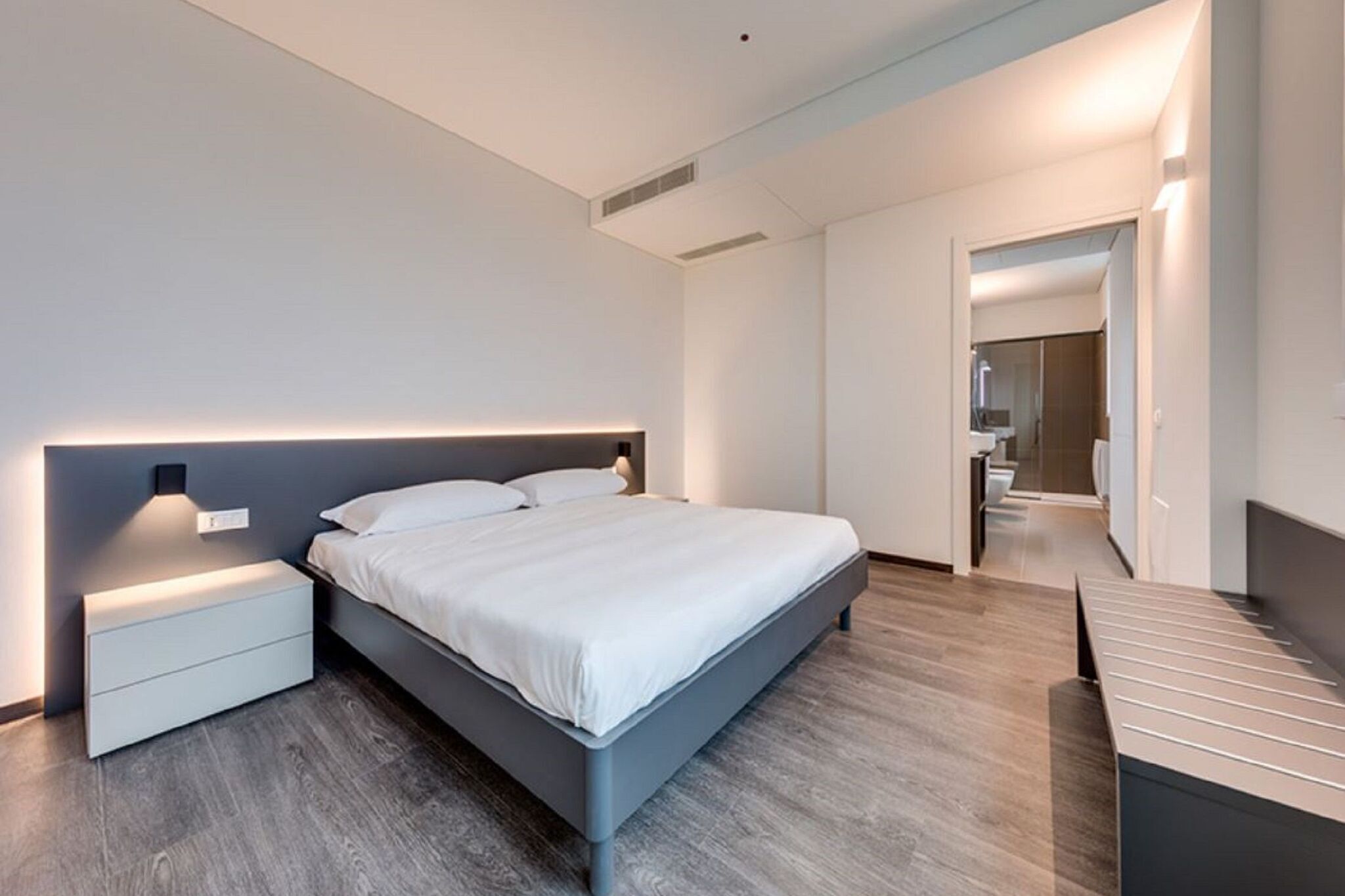 Ein modernes Schlafzimmer mit Bett, Nachttischen und einer Bank.