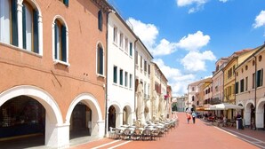A street with outdoor seating, buildings with arched windows, and a clear sky. - Belvilla by OYO Appartamento N10 (Venice)