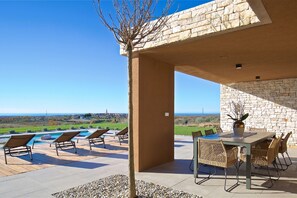 An outdoor patio with a pool, lounge chairs, and a dining table with chairs. - Enticing Holiday Home in Brtonigla with bubble bath (Brtonigla)