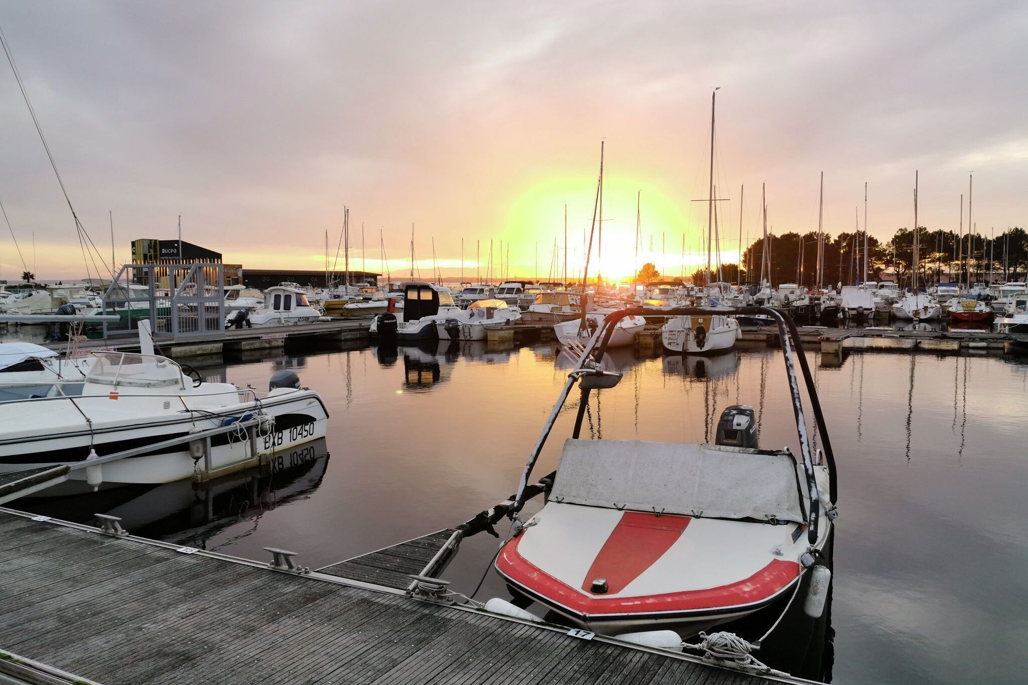 A marina with boats docked, a building labeled "Bucro", and a sunset in the background.