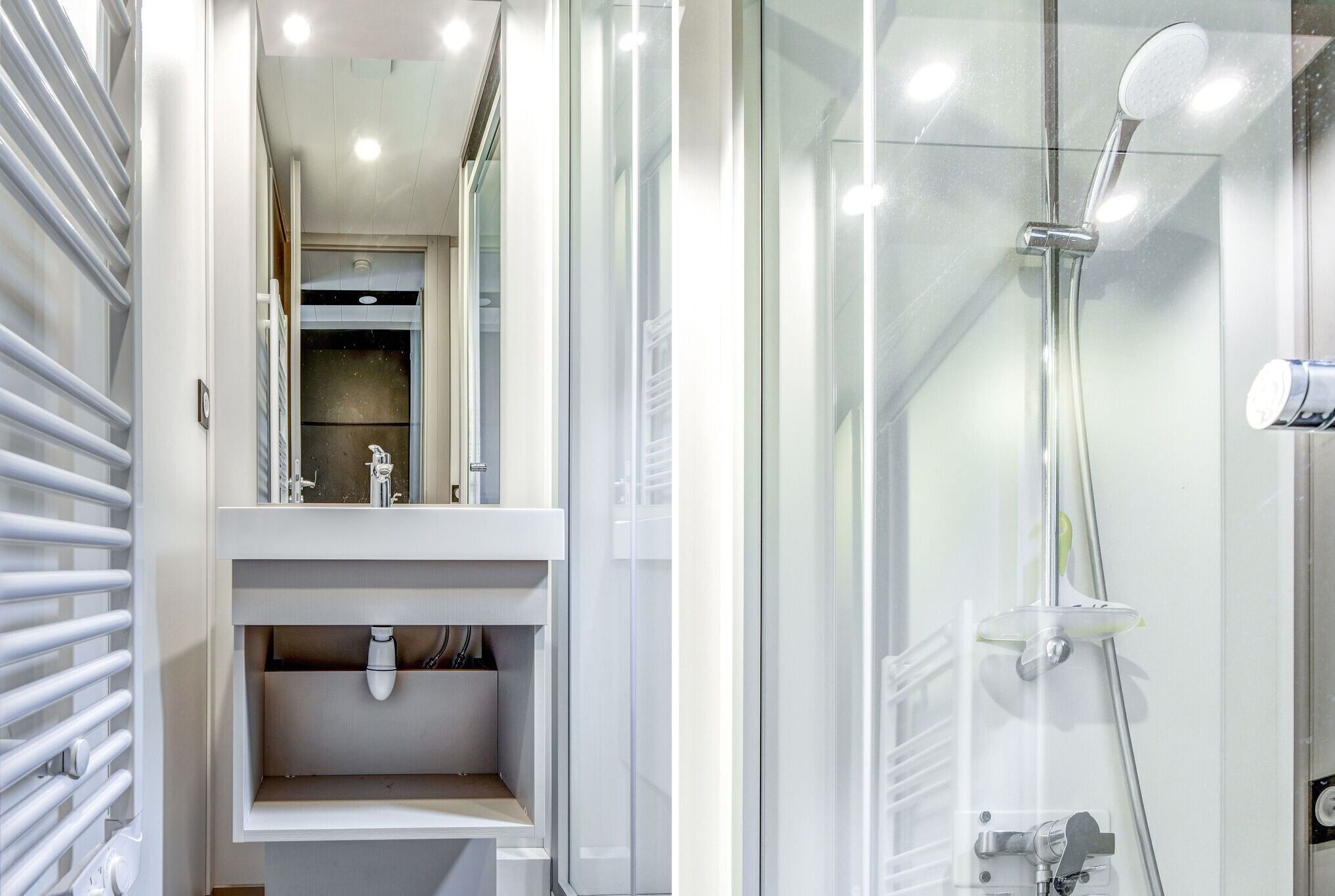 Een moderne badkamer met een douchecabine van glas, een witte wastafel met spiegel en een toilet.