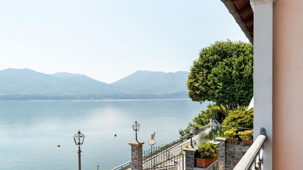 Un balcon offrant une vue sur un lac paisible et des montagnes lointaines.