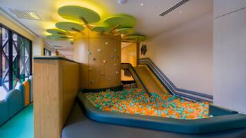 A children's play area with a slide, climbing wall, and ball pit.