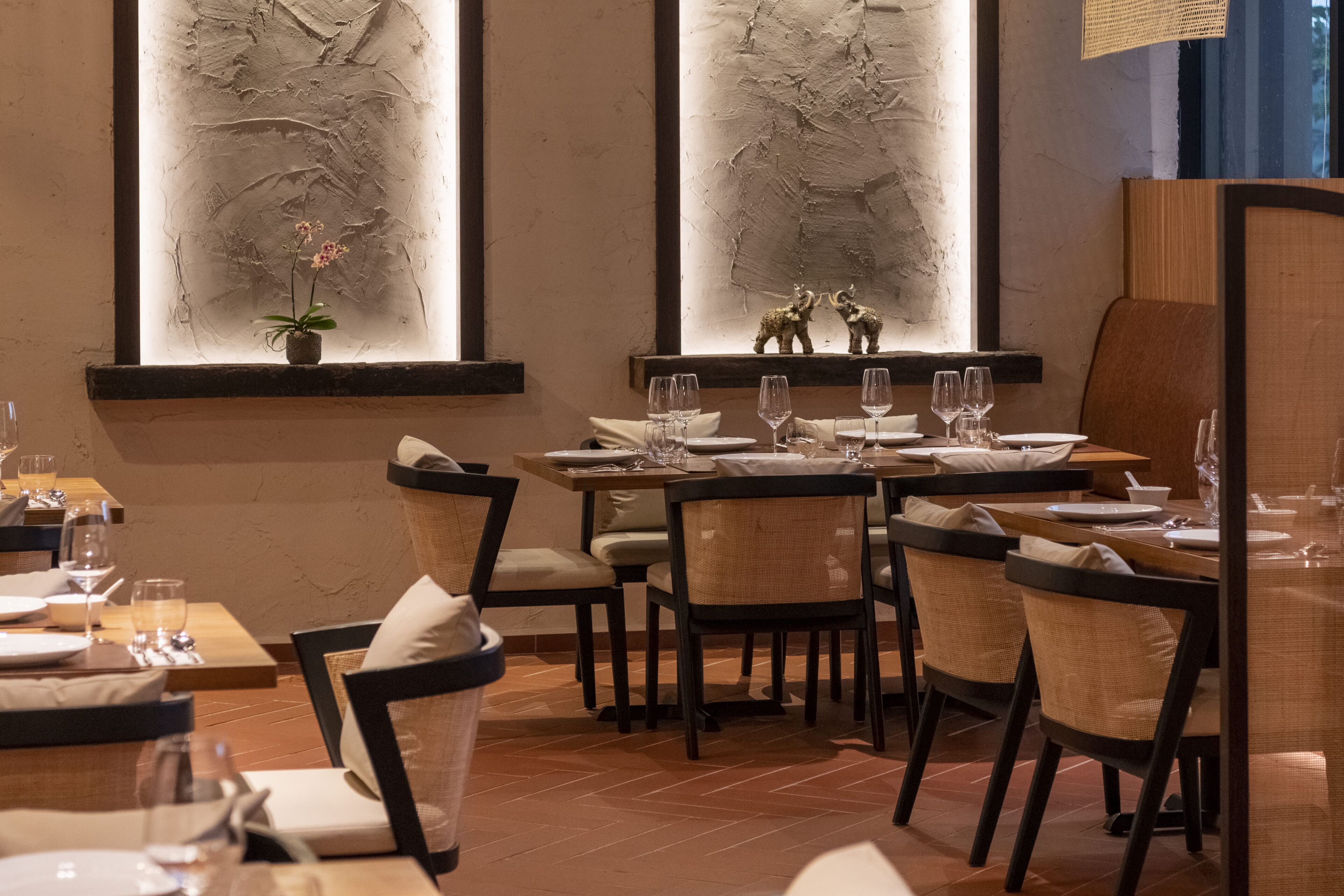A restaurant with multiple tables and chairs, each set with plates, glasses, and cutlery.