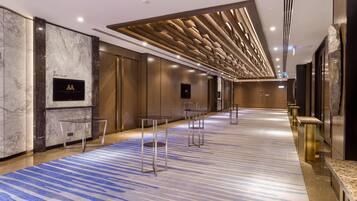 A spacious hotel lobby with marble walls, a patterned carpet, and modern lighting fixtures.