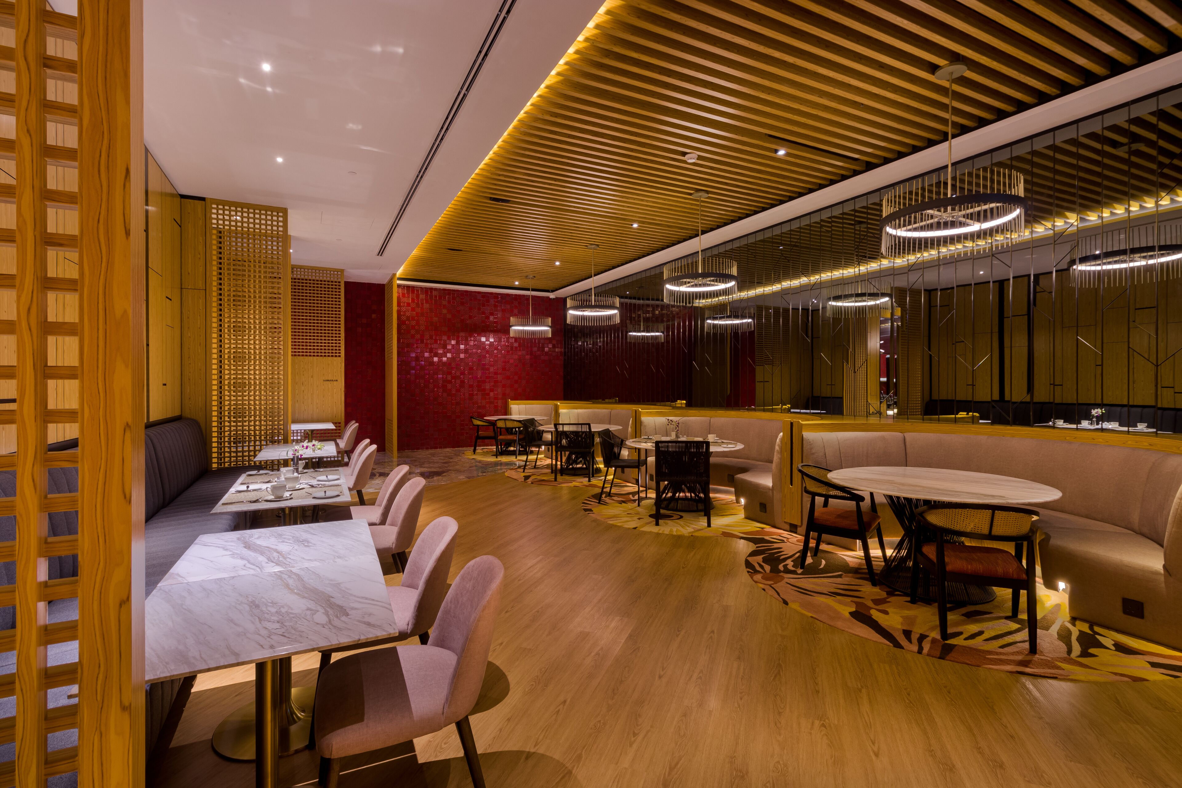 Un espace de restauration moderne avec un lambris en bois, des touches de rouge et des luminaires contemporains.
