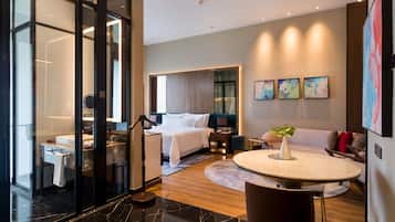 A modern hotel room with a bed, a desk, a round table, and a sofa.