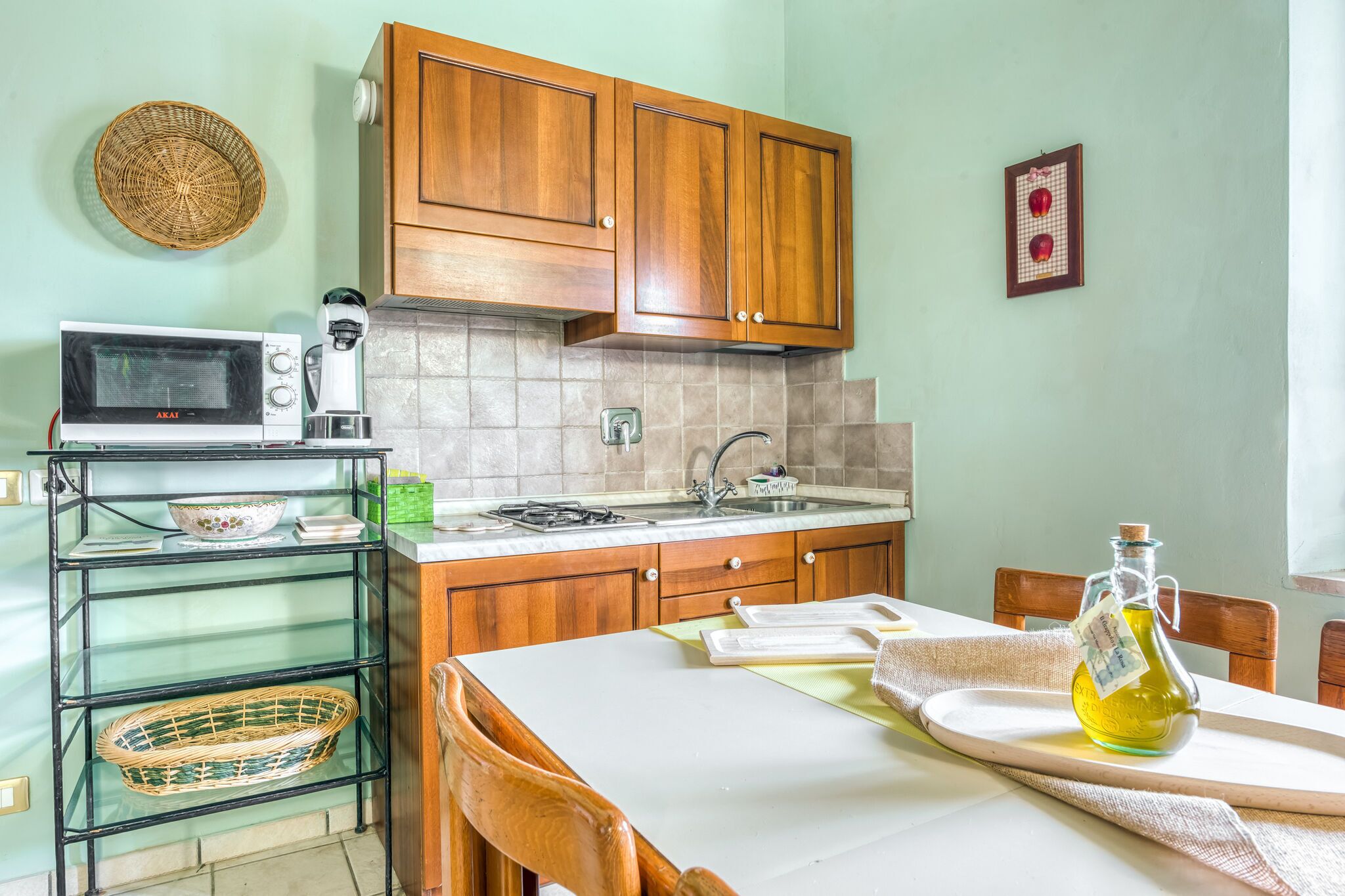 A kitchen with wooden cabinets, a microwave, a coffee maker, and a dining table with chairs.