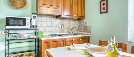 A kitchen with wooden cabinets, a microwave, a coffee maker, and a dining table with chairs.