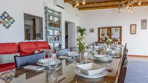 A dining area with a long table set for a meal, a red sofa, and a bookshelf. - Rural House Maimones. (Los Pérez)