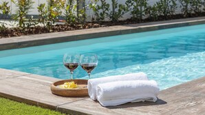 A poolside setting with two glasses of red wine, a bowl of chips, and a rolled white towel on a wooden deck. - Rural House Maimones. (Los Pérez)