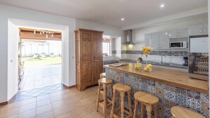 A modern kitchen with a large island, bar stools, and a view to the outside. - Rural House Maimones. (Los Pérez)