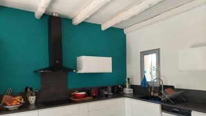 Una cocina moderna con gabinetes blancos, una campana extractora negra y una pared de acento color turquesa.