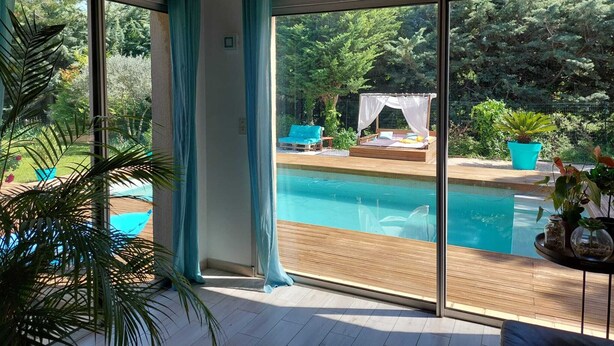 Una habitaci ón moderna con ventanas amplias, una piscina y una terraza de madera.