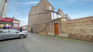 A street with a brick building, a car parked on the side, and a Bingo sign in the background. - Modern Studio in London near Wimbledon Park (London)