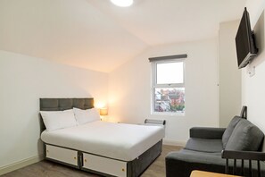 A bedroom with a bed, a chair, a TV, and a window. - Modern Studio in London near Wimbledon Park (London)