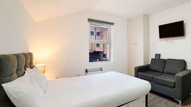 A bedroom with a bed, a window, a TV, and a sofa. - Modern Studio in London near Wimbledon Park (London)