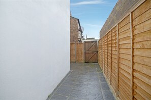 A narrow stone-paved alleyway flanked by wooden fences and a white wall. - Modern Studio in London near Wimbledon Park (London)