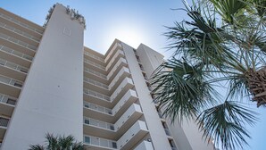 A high-rise building with multiple balconies and a palm tree in the foreground. - Beachfront 2Br, 2 Bath at Dunes of Panama- Sleeps 8  (3 pools, one heated) (Panama City Beach)