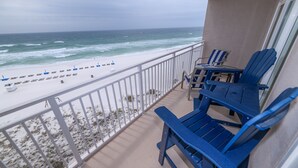 A balcony with blue chairs and a table overlooking a beach with a white sandy shore and ocean waves. - Beachfront 2Br, 2 Bath at Dunes of Panama- Sleeps 8  (3 pools, one heated) (Panama City Beach)