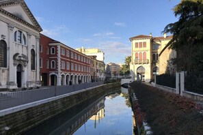 Ein Kanal, der von Gebäuden gesäumt ist, darunter ein rotes Gebäude mit Rundbogenfenstern und ein weißes Gebäude mit Säulen.