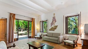 A spacious living room with a large window, a sofa, a wooden coffee table, and a chair.