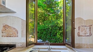 A kitchen with a large window, a sink, and a stove.