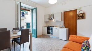 A compact living space with a dining area, kitchenette, and a sofa. - Holiday Home in Scicli near Palazzo Ribera (Scicli)