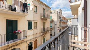A narrow street with buildings featuring balconies and shutters. - Holiday Home in Scicli near Palazzo Ribera (Scicli)
