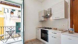 A compact kitchen with a gas stove, oven, and white cabinets. - Holiday Home in Scicli near Palazzo Ribera (Scicli)