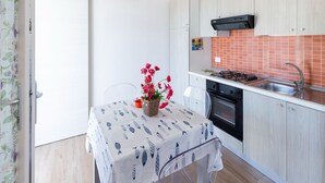 A compact kitchen with a gas stove, oven, and a small dining area with a table and chairs. - Villa in Favignana with Pool & Near the Sea (Favignana)