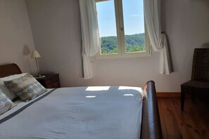A bedroom with a bed, a nightstand, a chair, and a window with curtains. - Picturesque holiday home with private pool (Seillans)
